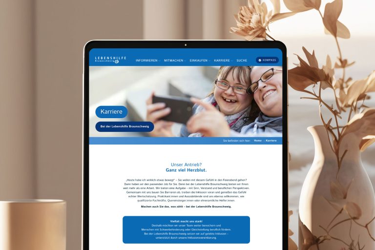 Karriereseite der barrierefreien Website der Lebenshilfe Braunschweig auf einem Tablet. Zwei lachende Frauen – eine mit Down-Syndrom – machen gemeinsam ein Selfie. Webdesign von Grafikstudio Carreira mit Fokus auf Inklusion und Teilhabe.